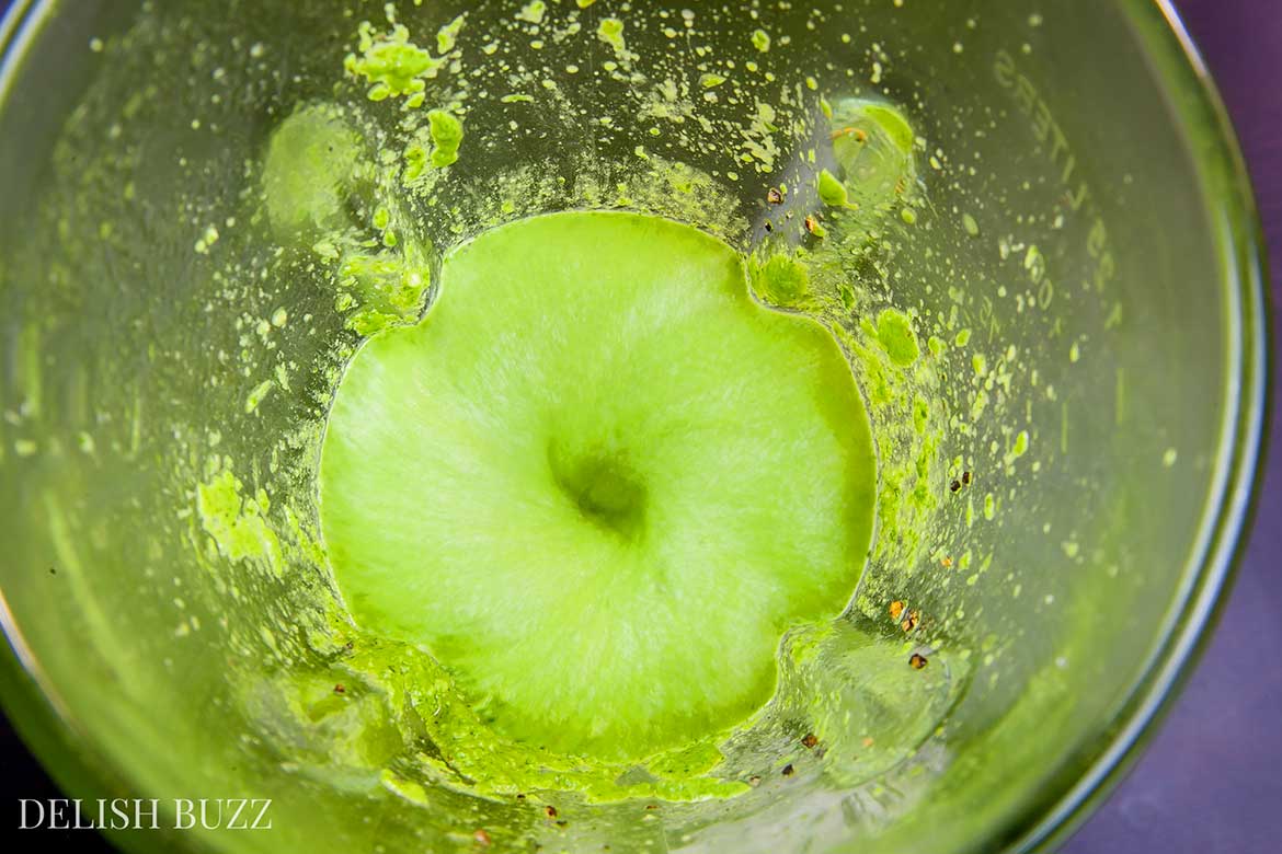 Vegan pesto is being blended. This simple pesto is made from fresh parsley and raw cashews. Vegan cashew pesto is so versatile that it can be used in many things beyond pastas. It has the yummy deep richness of greens and zesty aromas of fresh herb - www.delishbuzz.com