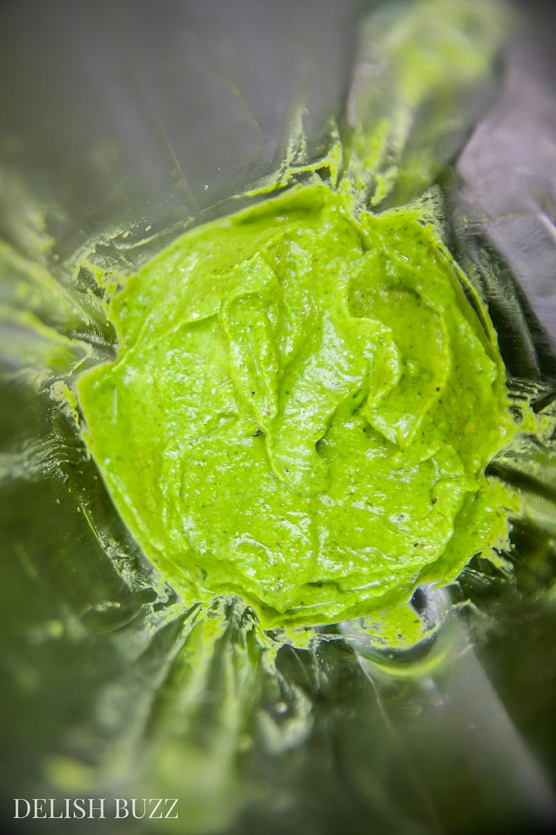 Vegan pesto is being blended. This simple pesto is made from fresh parsley and raw cashews. Vegan cashew pesto is so versatile that it can be used in many things beyond pastas. It has the yummy deep richness of greens and zesty aromas of fresh herb - www.delishbuzz.com