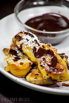 Vegan banana fritters are easy to whip up and are delicious. They have crispy golden outsides with delicious banana and melted caramel inside! Sparkling melted dark chocolate sauce adds extra yumminess. This luscious banana recipe is ready in minutes. www.delishbuzz.com