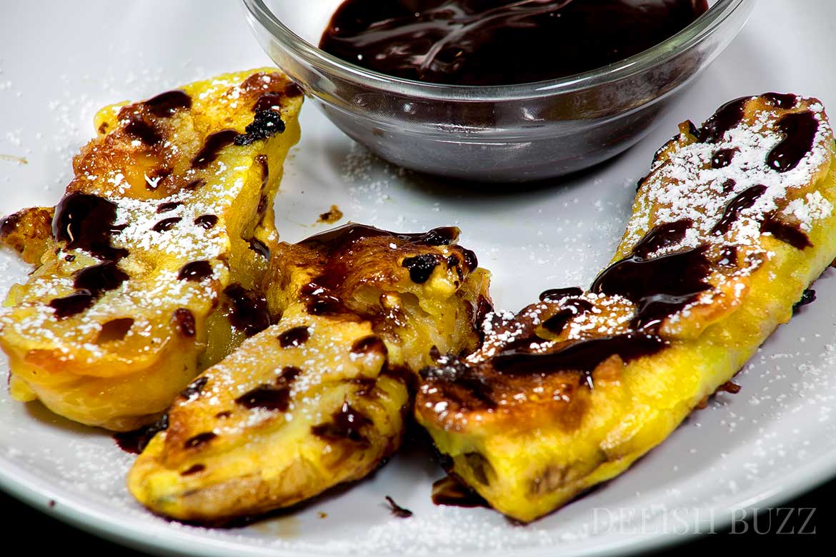 Caramel stuffed banana fritters with dark chocolate sauce. They have crispy golden outsides with delicious banana and melted caramel inside! Sparkling melted dark chocolate sauce adds extra yumminess. This luscious banana recipe is ready in minutes. www.delishbuzz.com