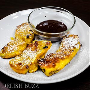 Vegan banana fritters are easy to whip up and are delicious. They have crispy golden outsides with delicious banana and melted caramel inside! Sparkling melted dark chocolate sauce adds extra yumminess. This luscious banana recipe is ready in minutes. www.delishbuzz.com