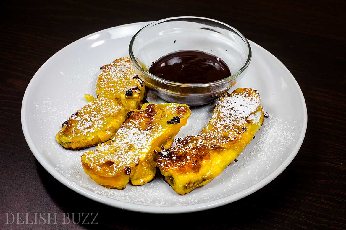 Vegan banana fritters are easy to whip up and are delicious. They have crispy golden outsides with delicious banana and melted caramel inside! Sparkling melted dark chocolate sauce adds extra yumminess. This luscious banana recipe is ready in minutes. www.delishbuzz.com