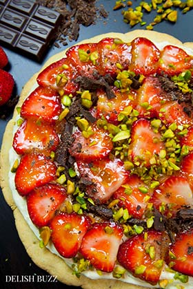 Easy delicious summery gluten free strawberry pizza. Very refreshing and full of subtle flavors. Strawberries on a sugar cookie crust with a layer of light lemon scented creamy frosting with apricot glaze. This will be a show stopper on any dining table. www.delishbuzz.com