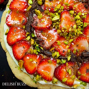 Easy delicious summery gluten free strawberry pizza. Very refreshing and full of subtle flavors. Strawberries on a sugar cookie crust with a layer of light lemon scented creamy frosting with apricot glaze. This will be a show stopper on any dining table. www.delishbuzz.com