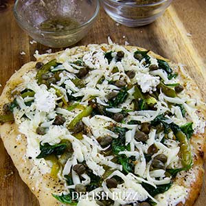 Beauty of a pizza in prep! So good and simple. Basil butter naan white pizza is as good as artisan pizzas. This recipe will make you realize how easy it is whip up a delicious flatbread pizza at home. - www.delishbuzz.com