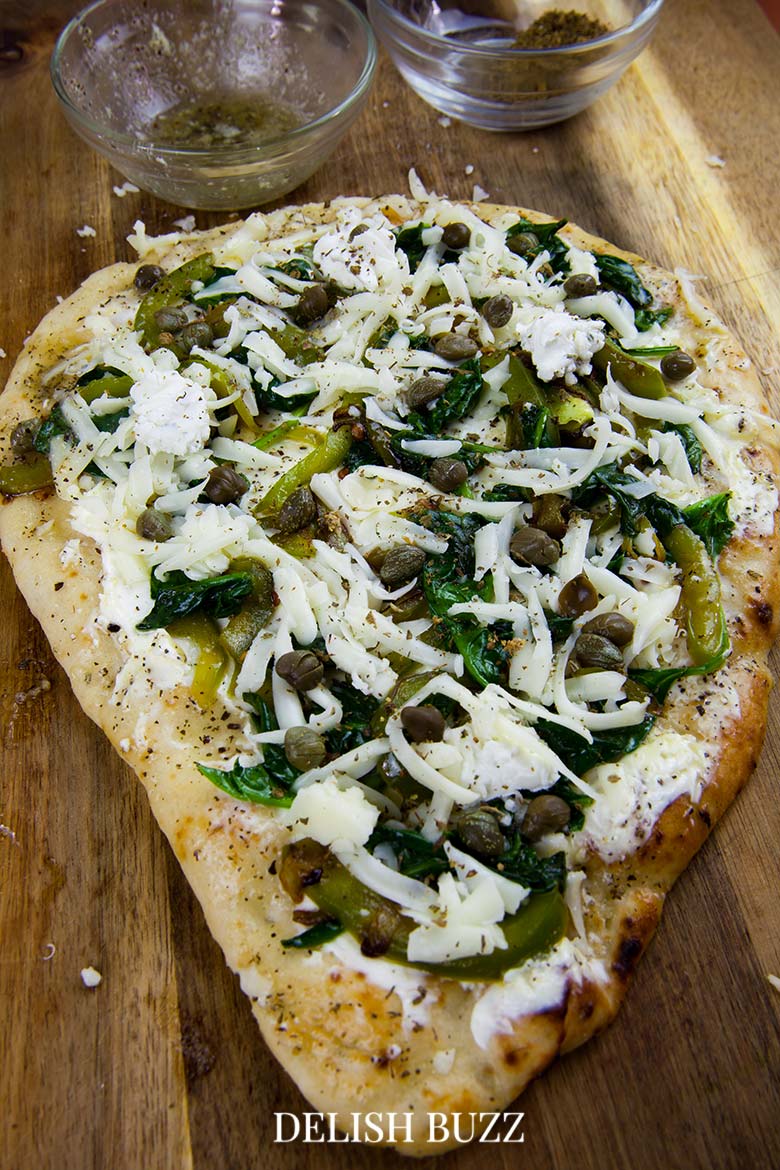 Beauty of a pizza in prep! So good and simple. Basil butter naan white pizza is as good as artisan pizzas. This recipe will make you realize how easy it is whip up a delicious flatbread pizza at home. - www.delishbuzz.com